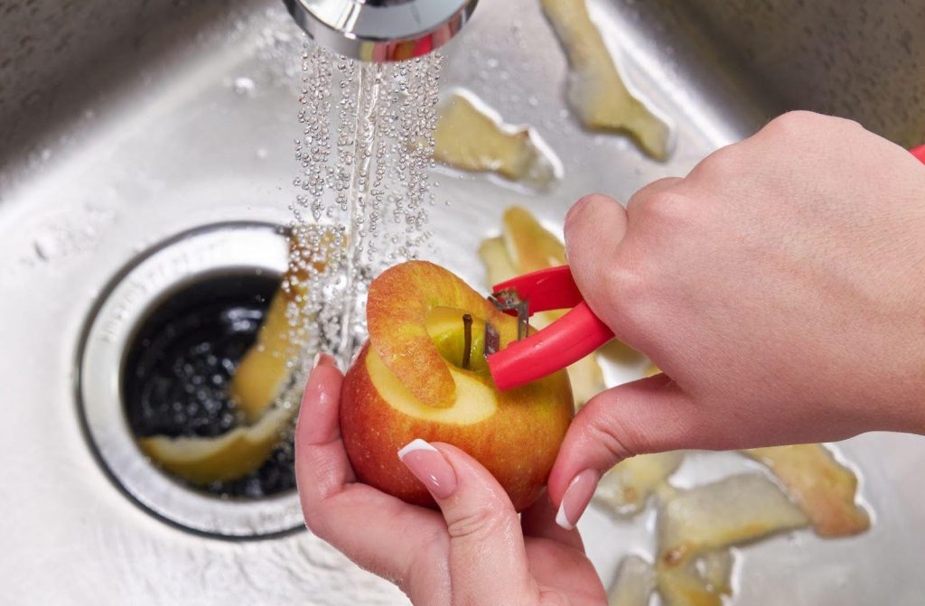 A person skillfully uses scissors to cut an apple into slices on a wooden surface