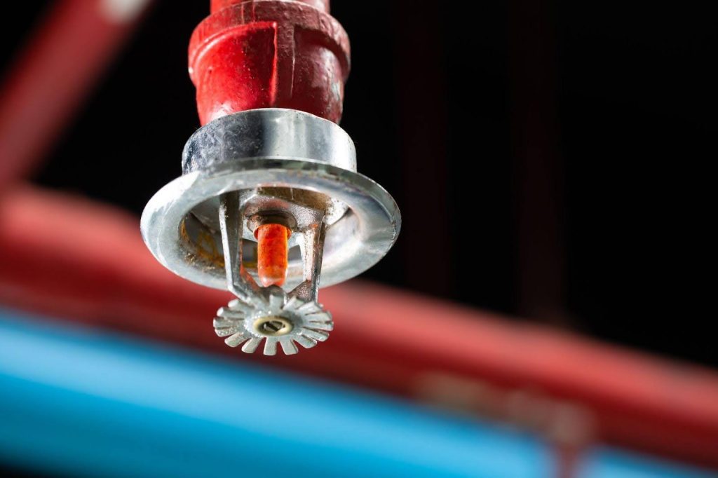 A red and white hanging light attached to a pipe, providing a striking visual contrast in the environment