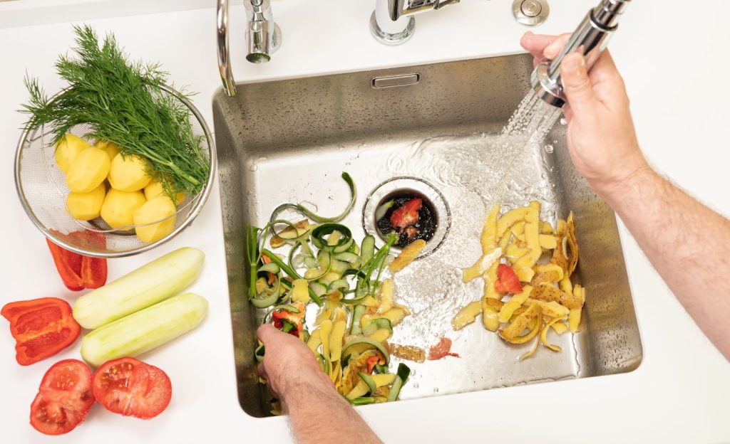 A person washing vegetables in a sink. The image depicts a common kitchen activity.