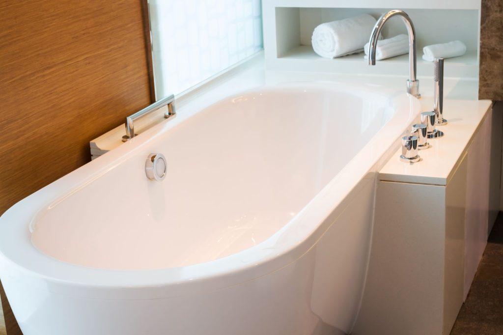 Professional plumber needed for installing a white bathtub in a bathroom renovation project.