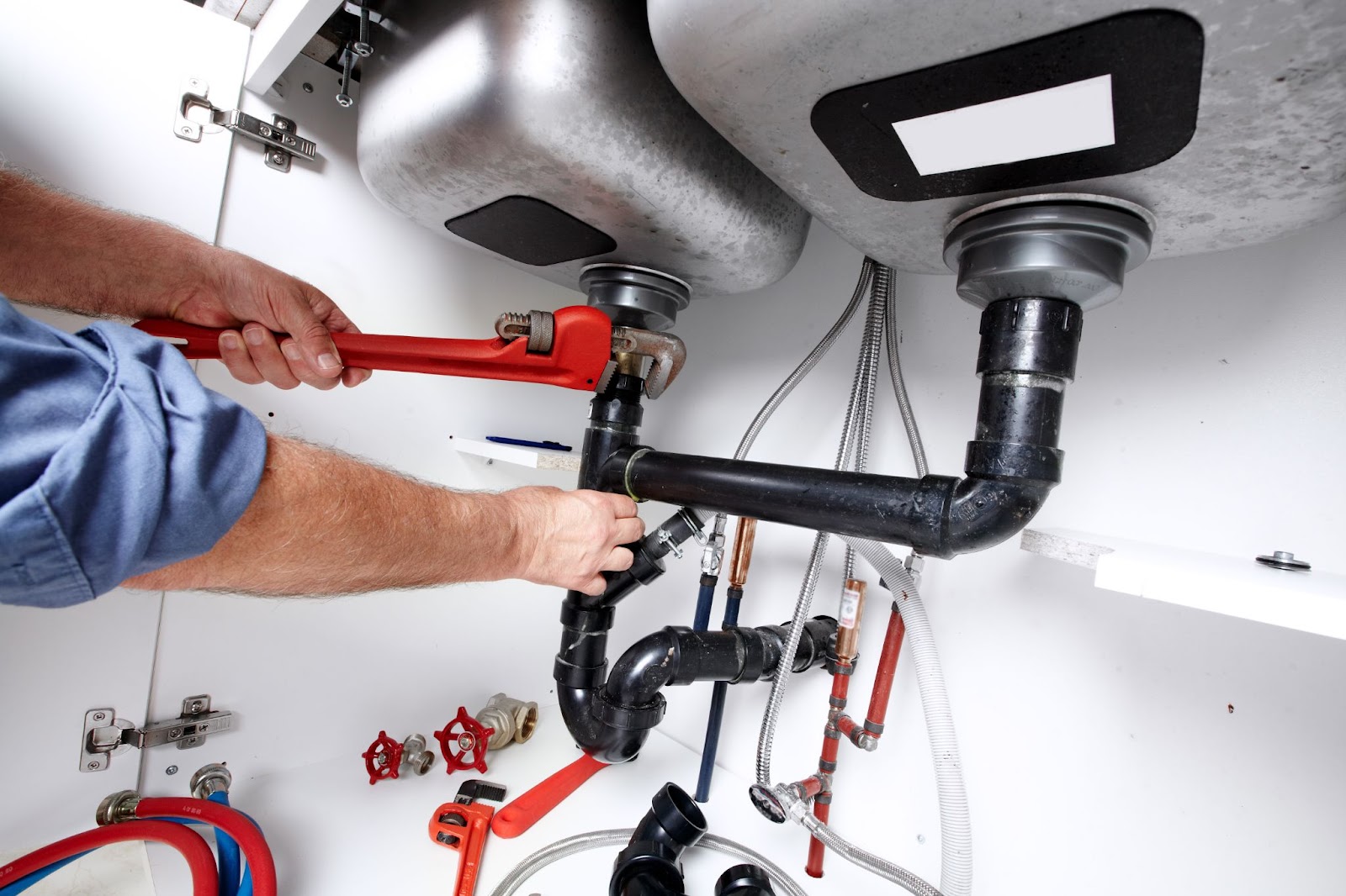 A man repairs a water heater in a room, showcasing the expertise of Utah plumbing contractors in commercial plumbing jobs.