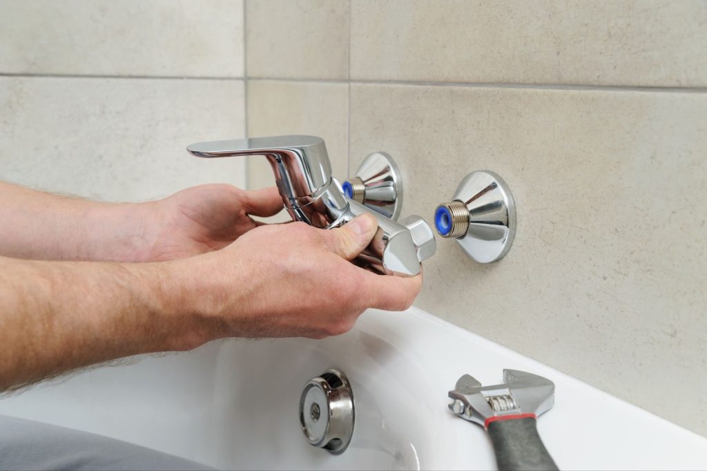 A plumber repairs a faucet in a bathtub, ensuring proper functionality for your shower or tub needs.