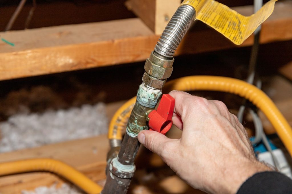 A professional installs a pipe to connect a water heater, focusing on the safety of commercial gas line systems.