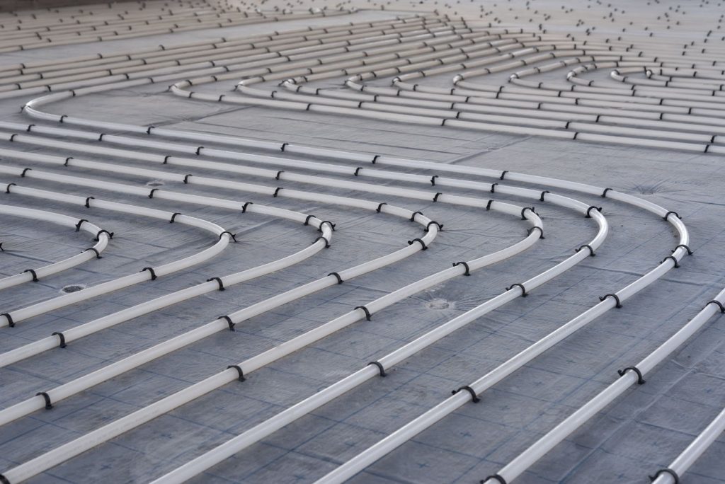 A vast array of pipes arranged on the floor, illustrating components of a radiant heating system for efficient warmth distribution.