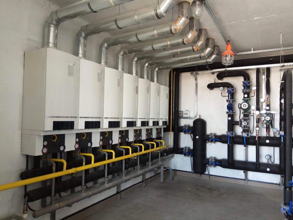 Room filled with pipes and valves, illustrating the process of managing plumbing in large apartment buildings.