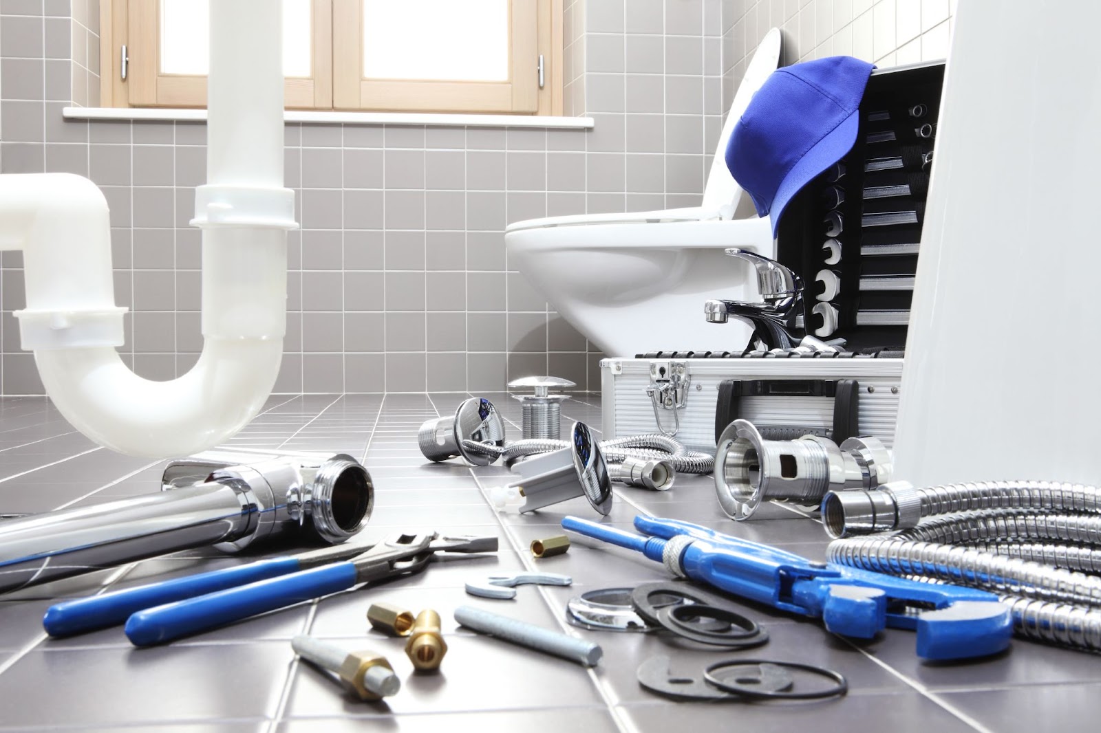 A collection of plumbing tools and supplies arranged on the floor, essential for professional plumbing maintenance and repairs.