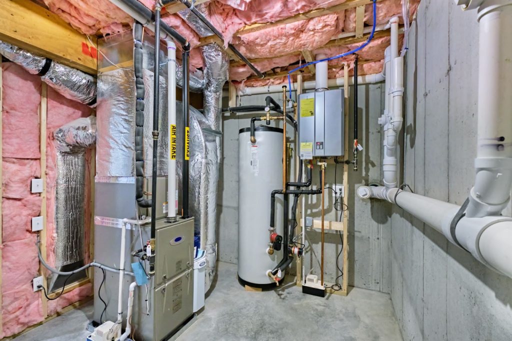 A room featuring a water heater and visible pipes, highlighting professional plumbing for water heater repair services.