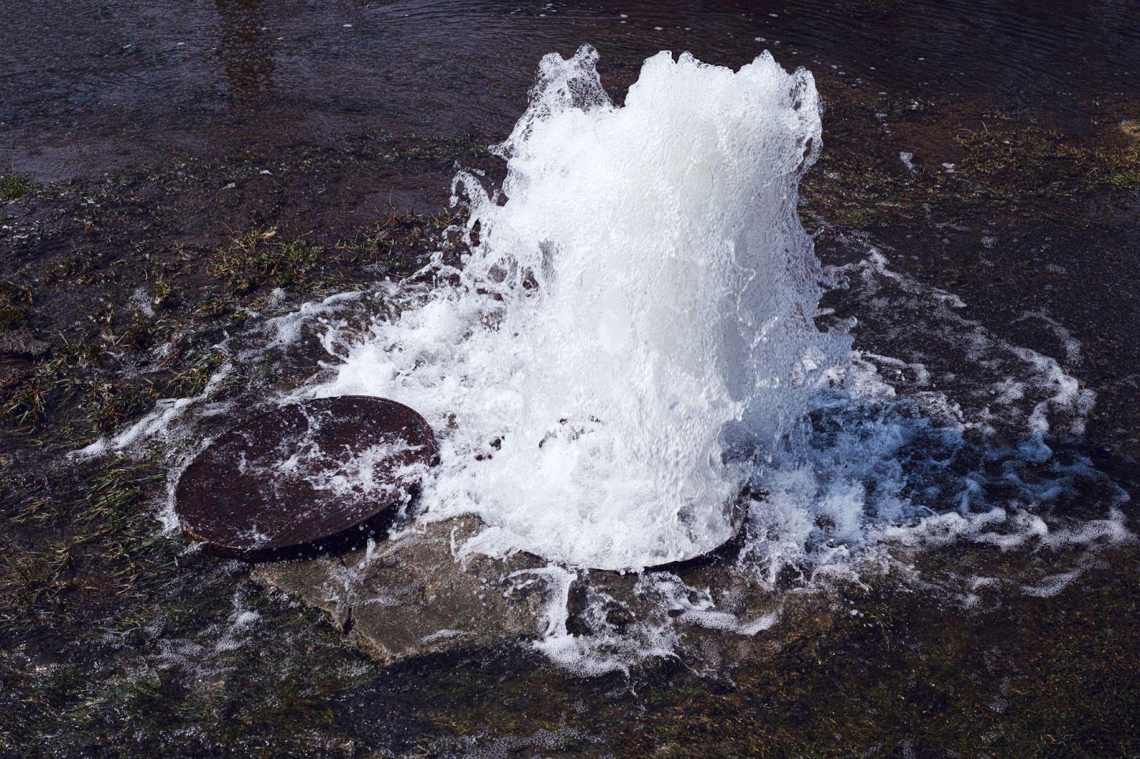 A fire hydrant sprays a powerful jet of water, creating a dynamic display of droplets