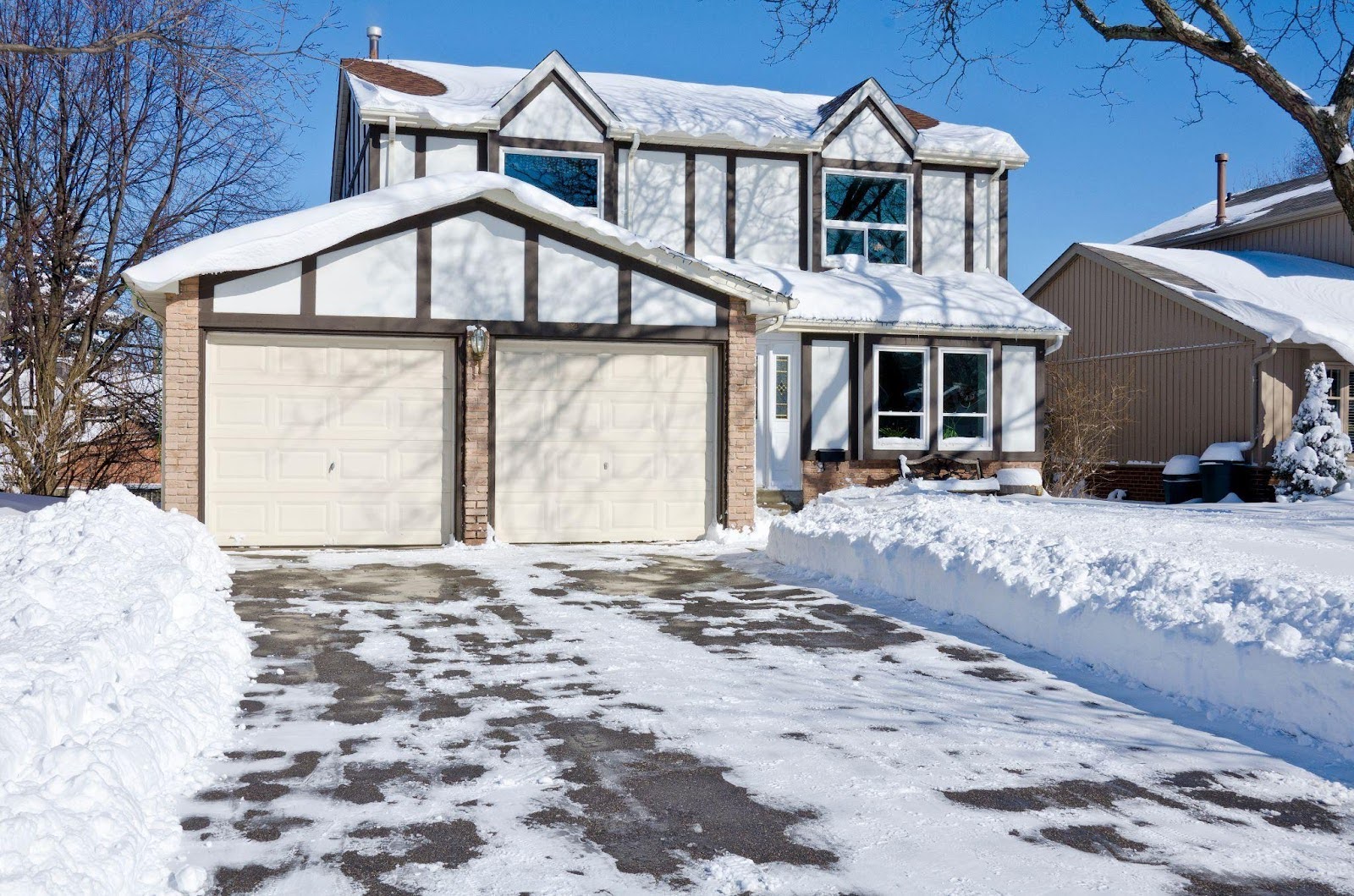 A grand house with a snowy driveway, showcasing a winter landscape