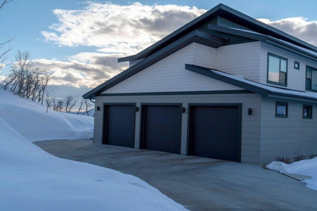 A spacious gray house set against a snowy ground, evoking a peaceful winter scene