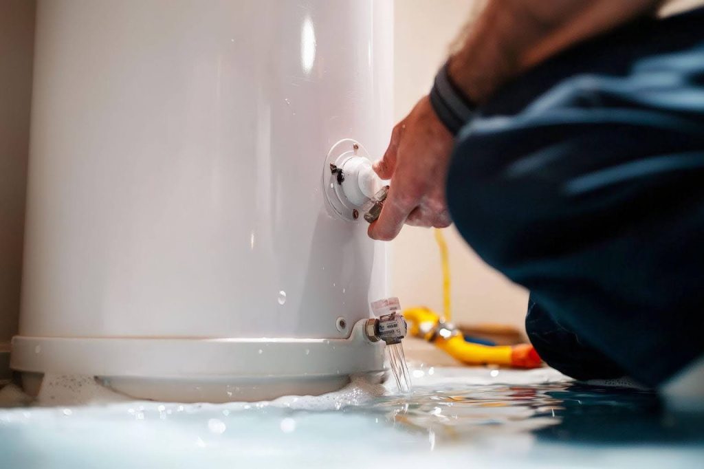 A man works on a water heater in a bathroom, utilizing tools and expertise to ensure proper functionality