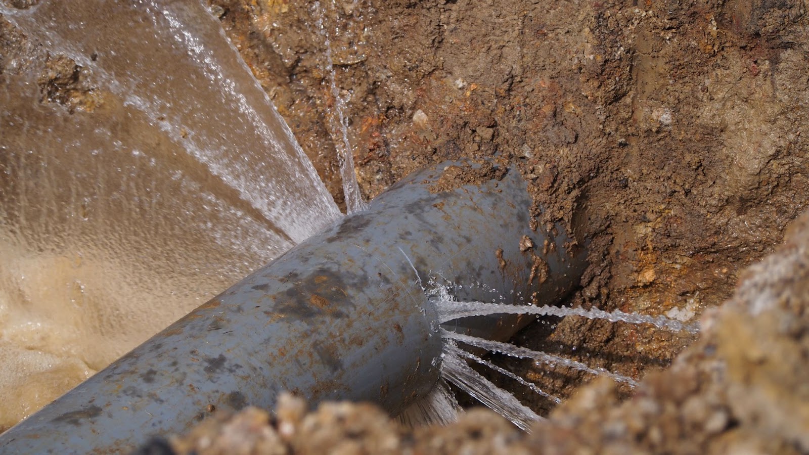 A leaking pipe from a water main, illustrating issues related to water supply infrastructure.