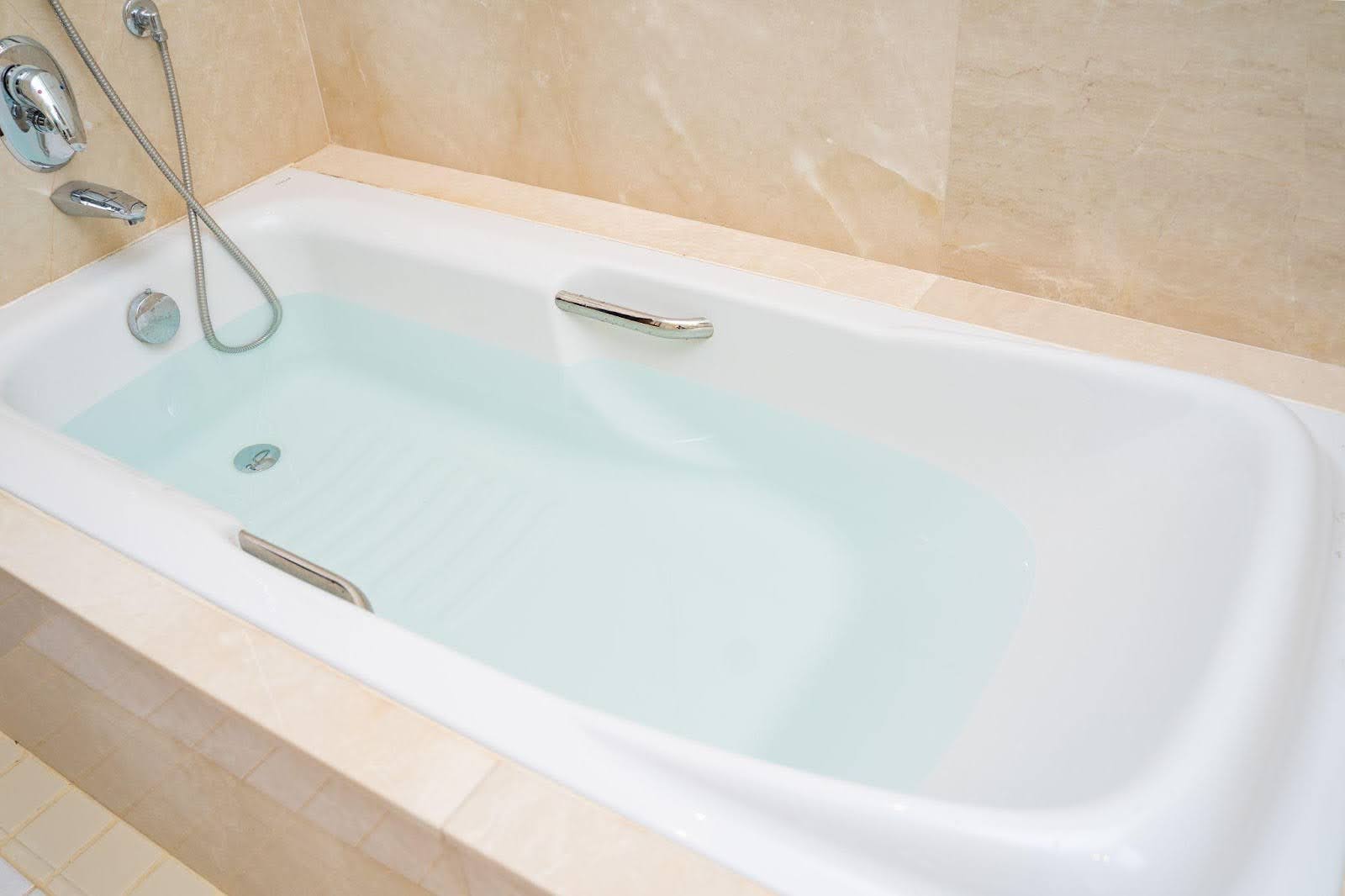 A modern bathtub with a fixed and handheld shower head for versatile bathing