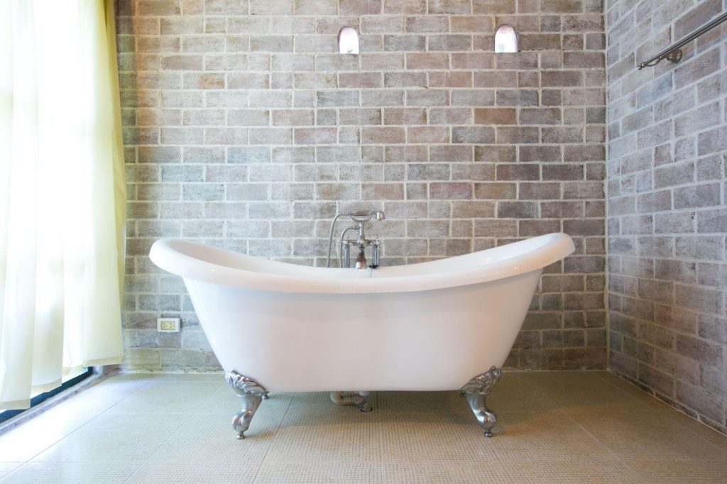 A white bathtub in a bathroom featuring rustic brick walls, creating a cozy and inviting atmosphere